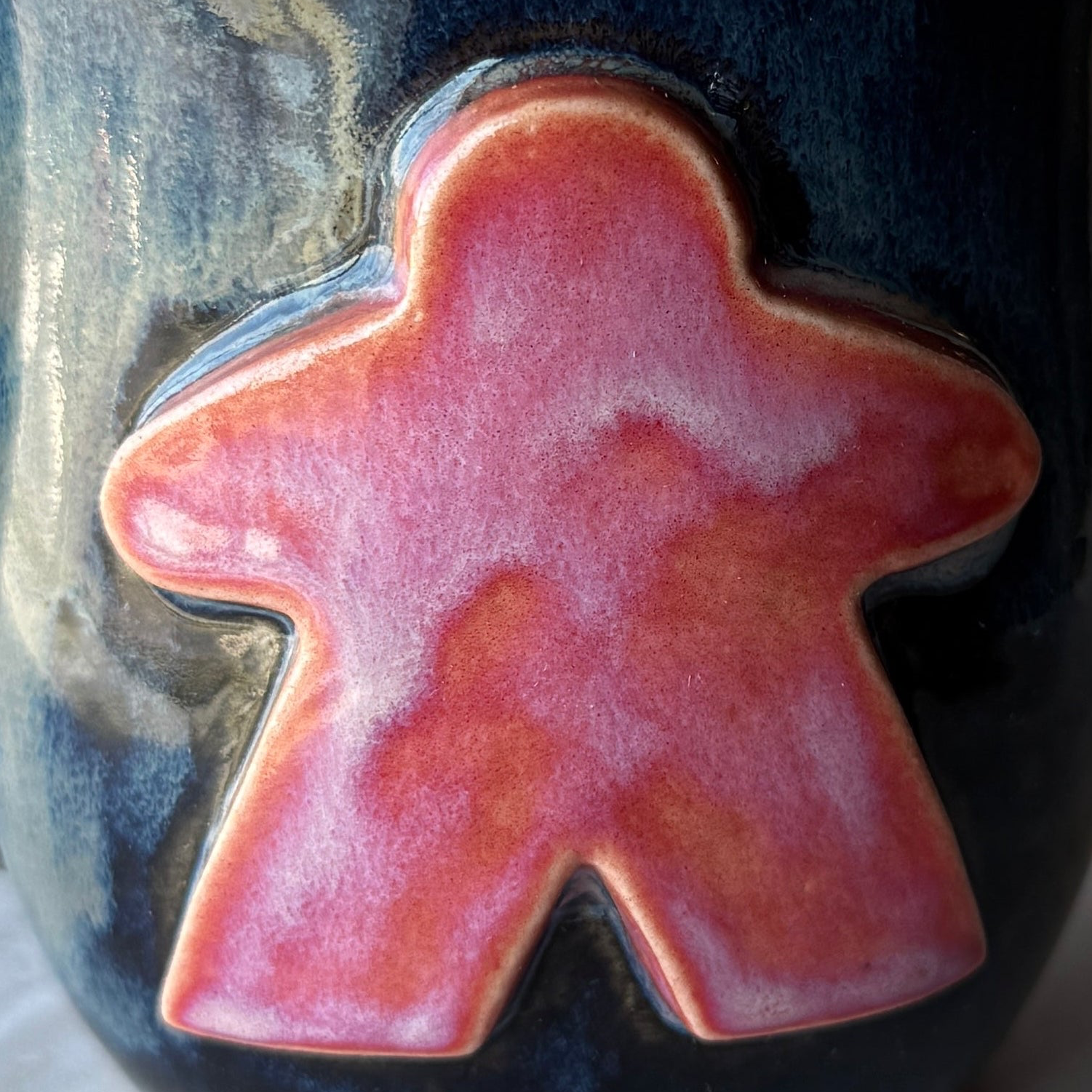 Hot pink ceramic meeple on a dark blue background